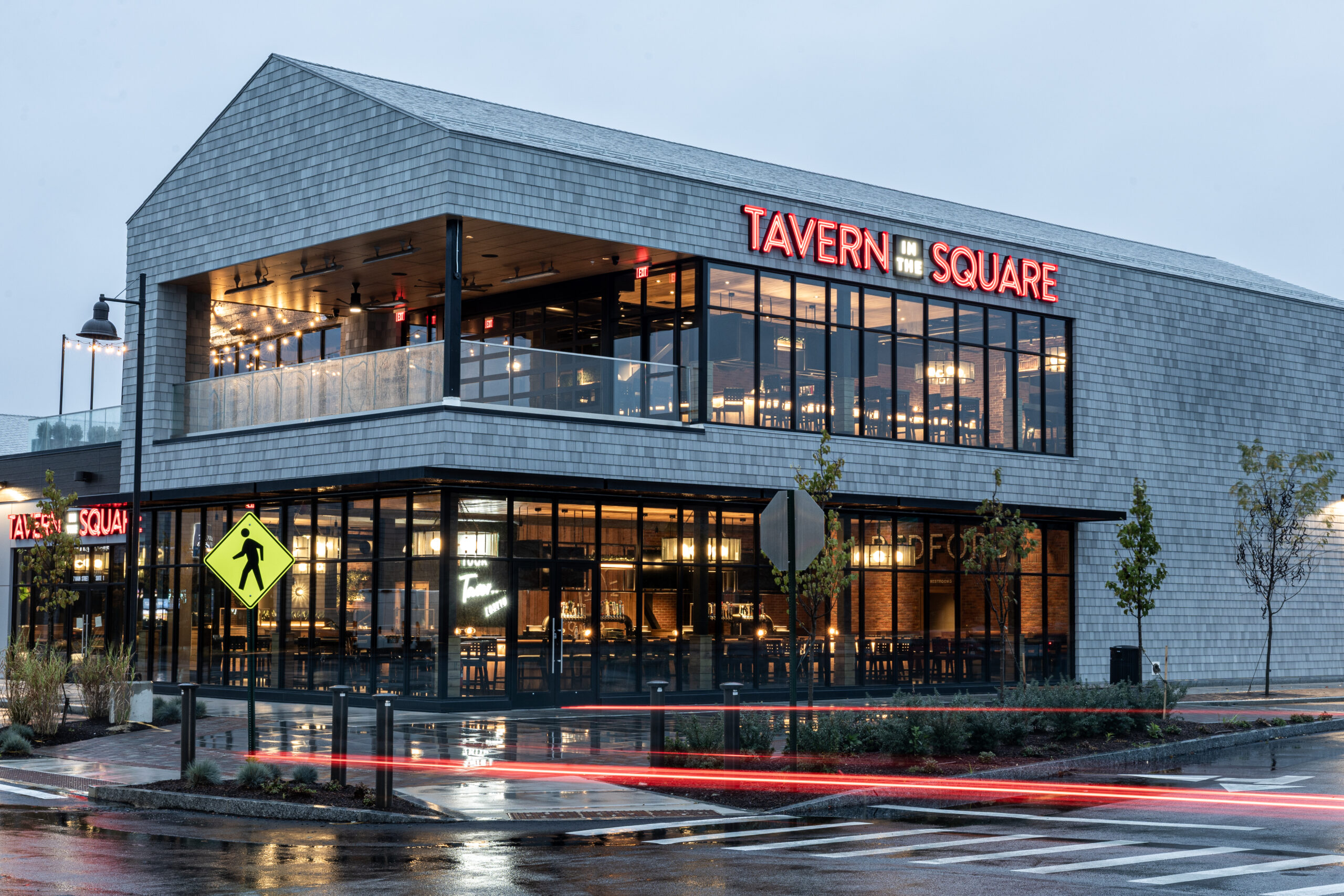 A modern two-story American Tavern with large windows and a sign reading 