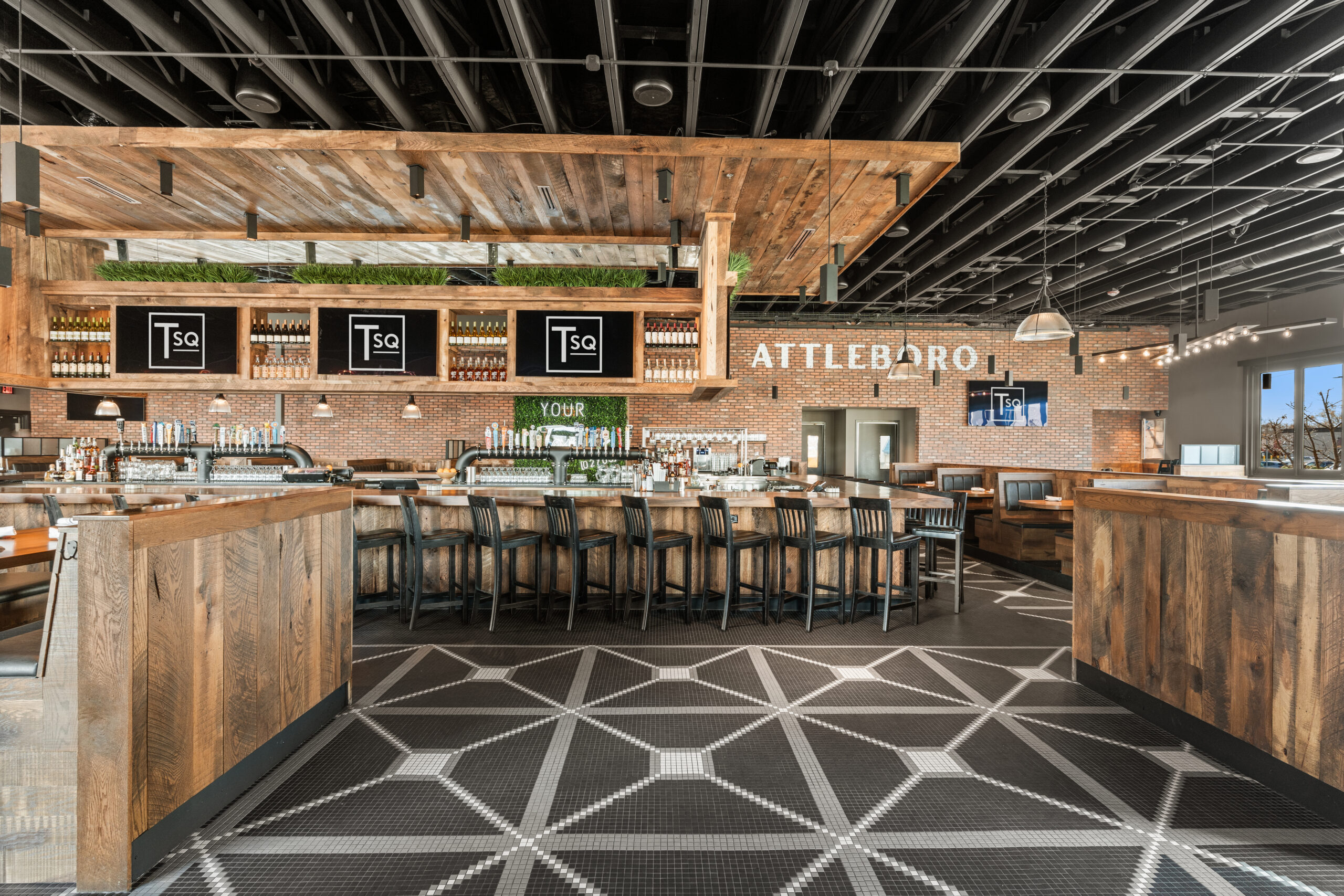 Modern Bar & Restaurant interior with wooden accents, geometric tile flooring, and a central bar area lined with black chairs. 