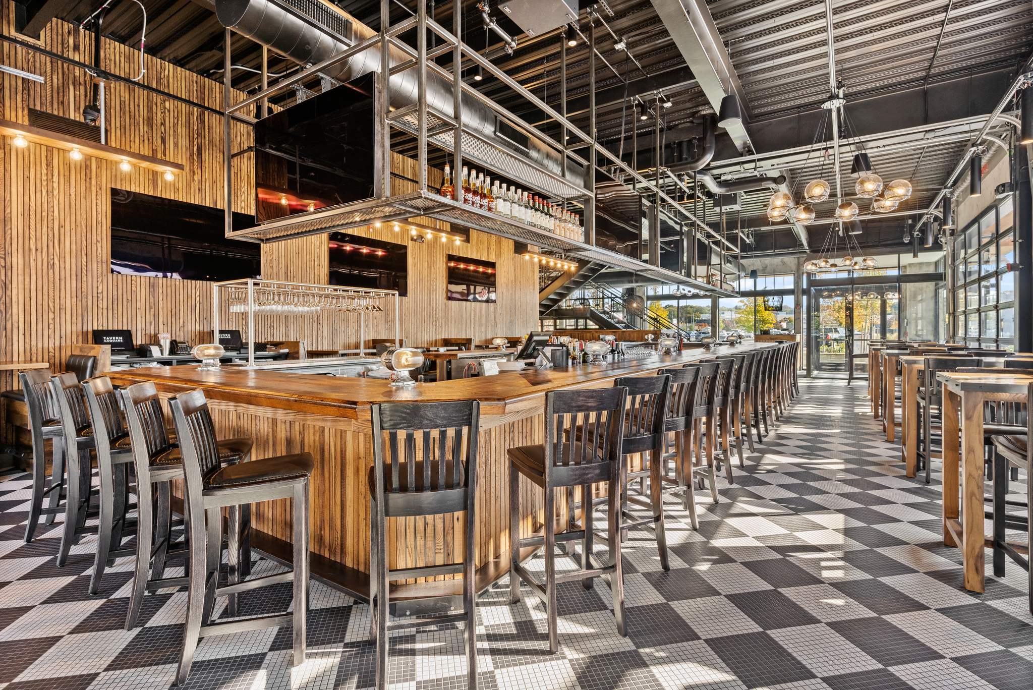 A large American Tavern bar & restaurant with chairs and a black and white checkered floor.