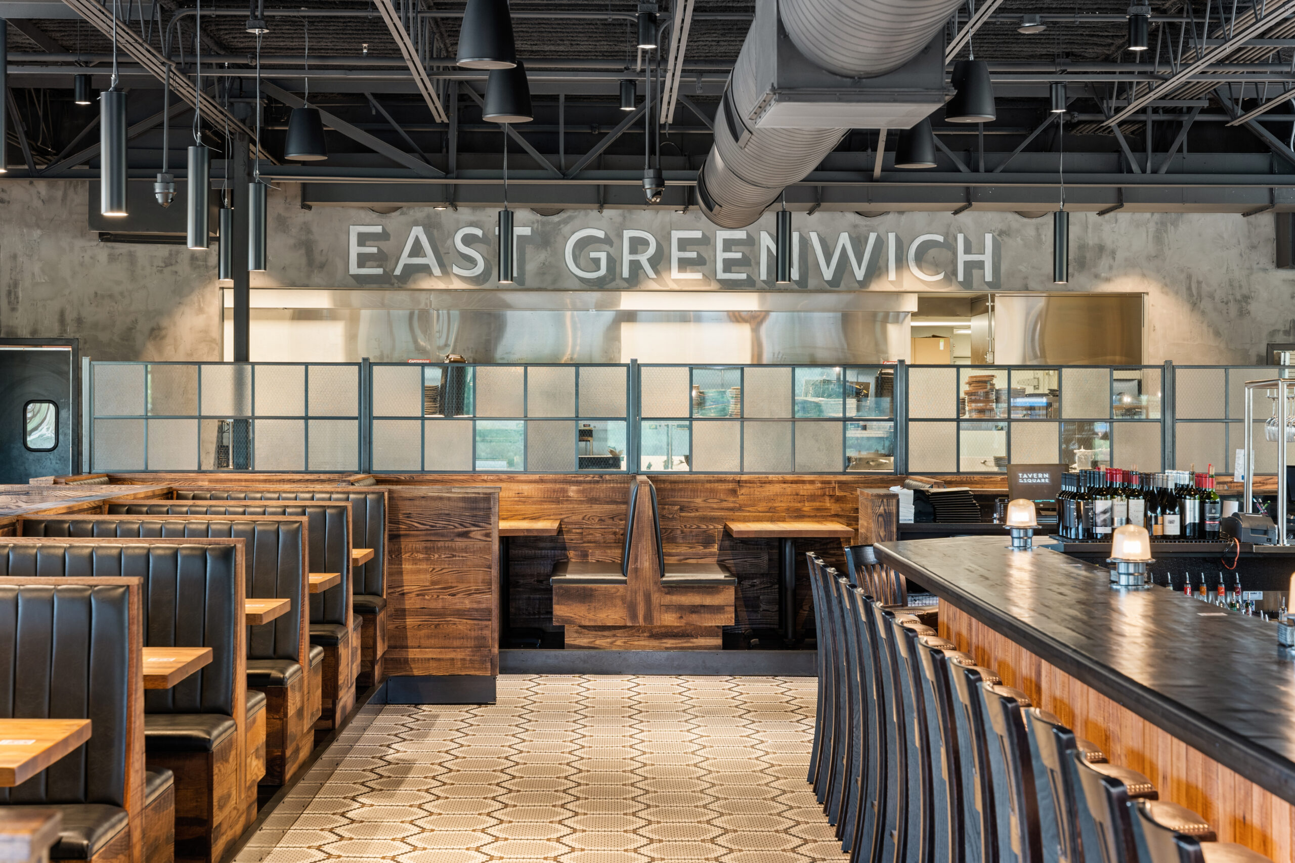 Modern Bar & Restaurant interior with black leather booths, wooden tables, a long bar, and 