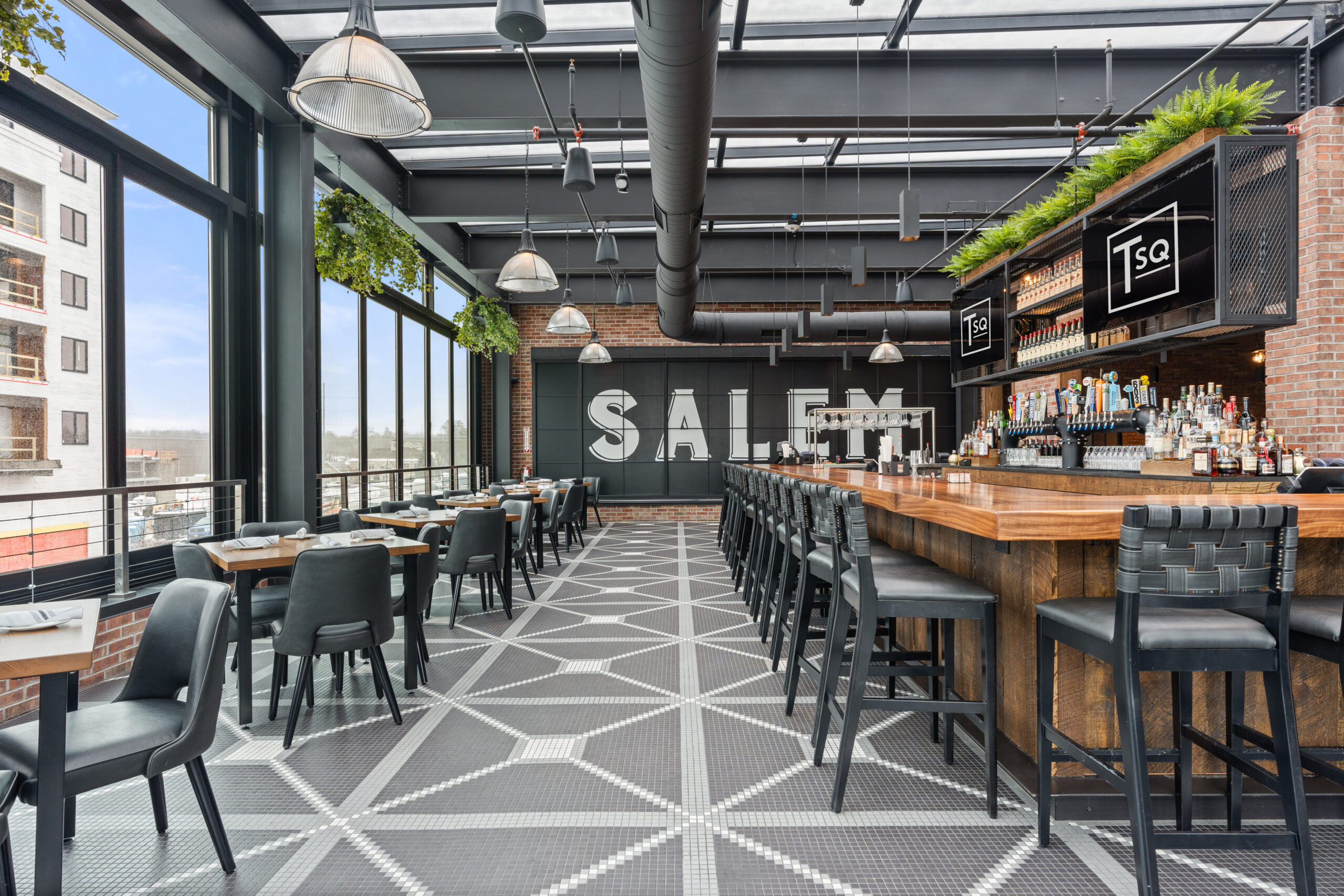 Modern Bar & Restaurant with large windows, high ceilings, geometric tiled floor, brick walls, and a long wooden bar; 