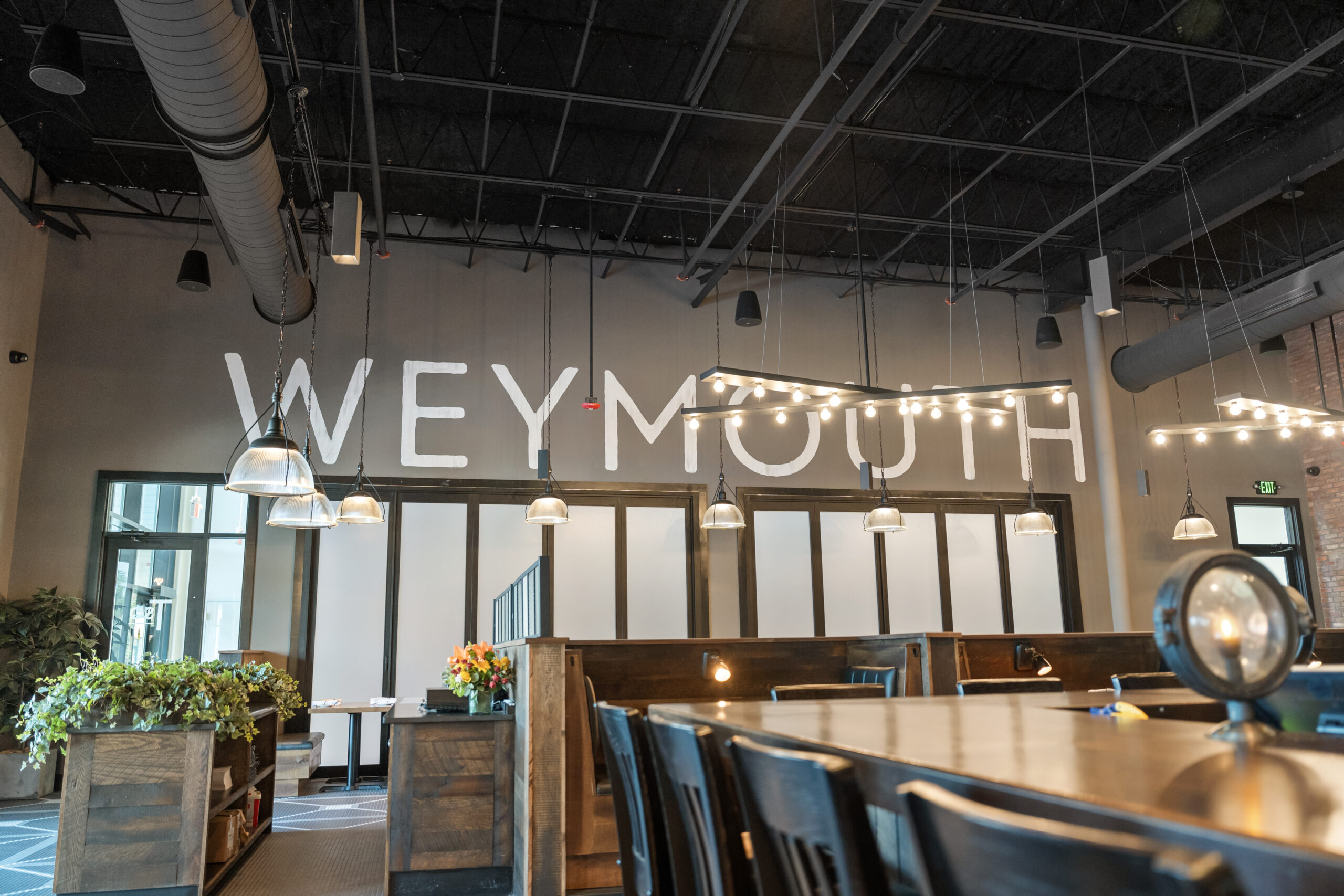 Modern indoor dining area with wooden tables, hanging lights, and large 