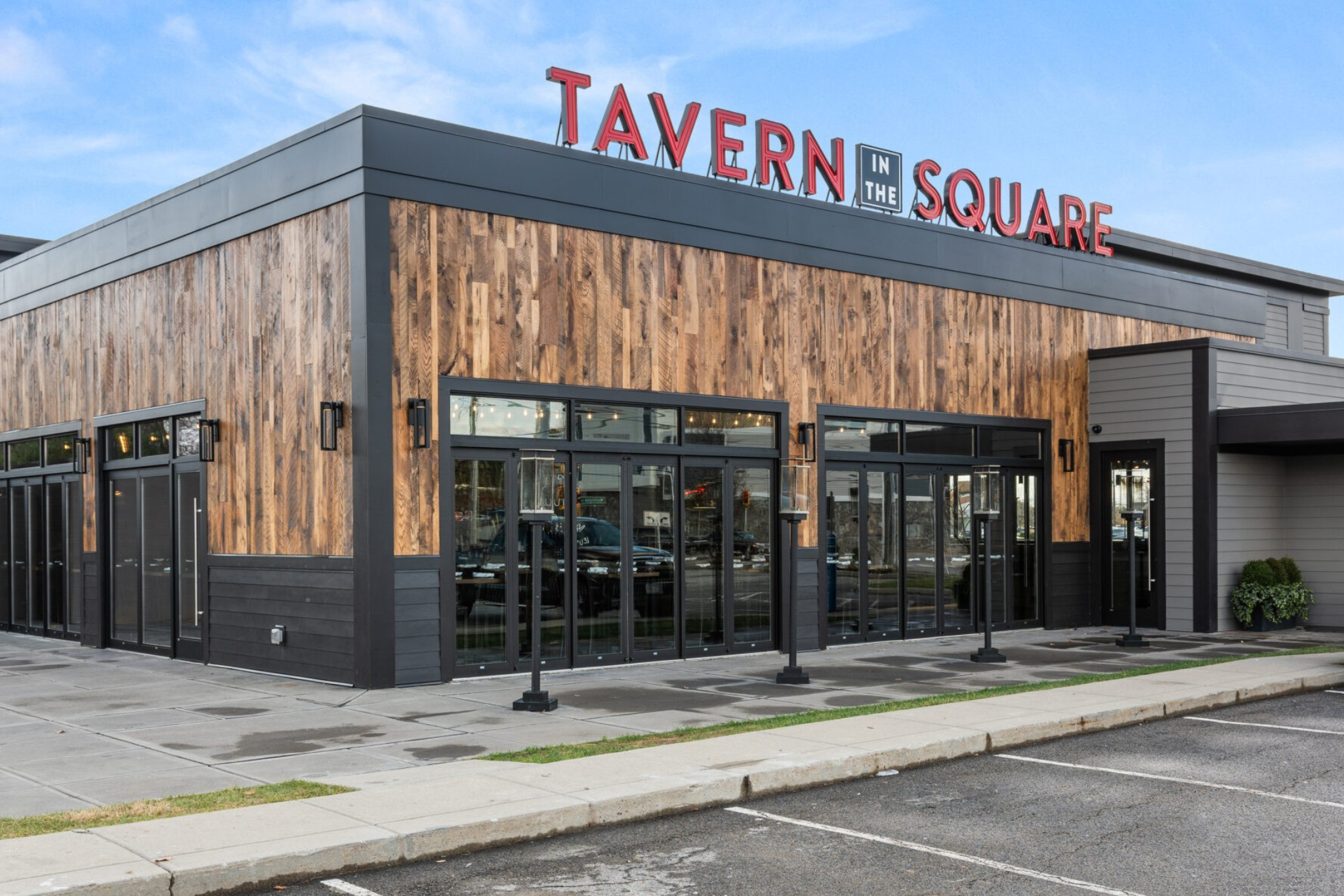 Exterior view of a modern building with large windows and wood paneling, displaying a sign that reads 