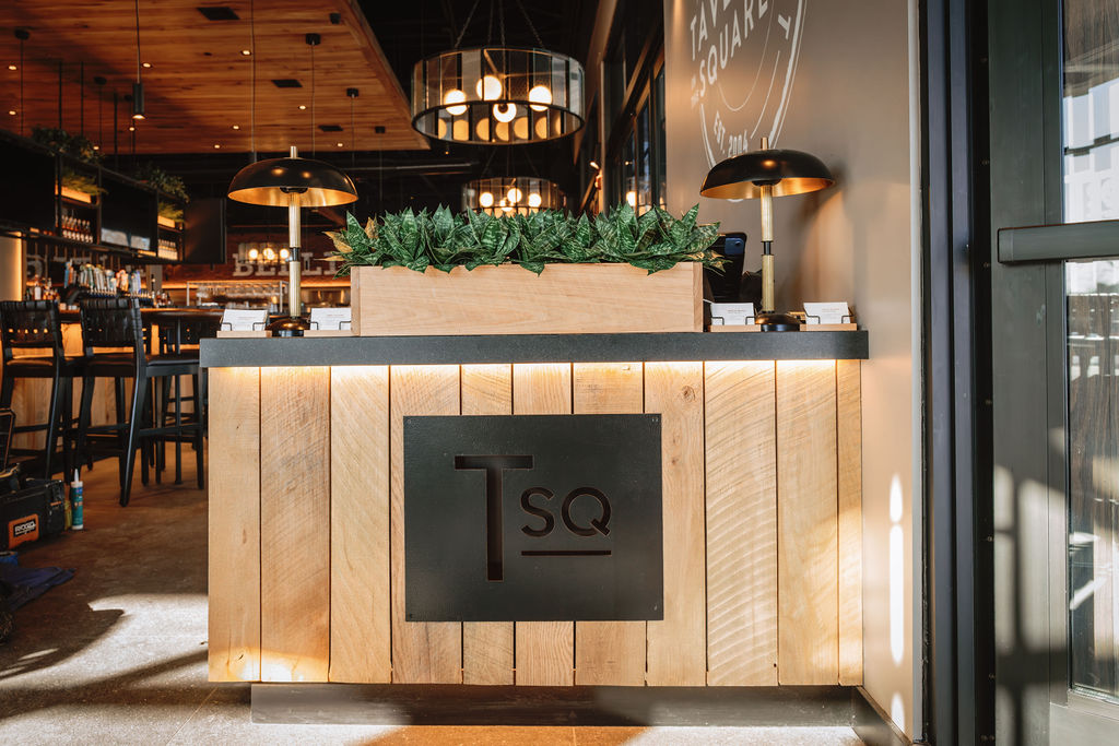 A wooden restaurant reception desk with a black 